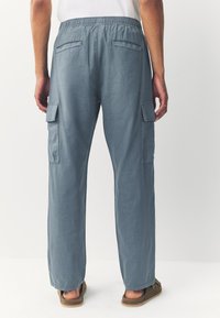 Light blue cargo pants with a relaxed fit, featuring side and back pockets and an elastic waistband, made from soft, textured fabric.