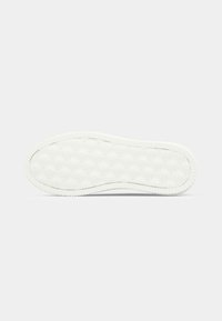 Semelle en caoutchouc blanc avec un bord texturé et un motif en relief de logo "cK" répété sur toute la surface inférieure.