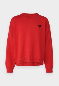 Pull en tricot rouge avec un col rond et des poignets côtelés. Un petit logo de cœur brisé noir est brodé à l'arrière.