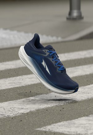 Πάνινο παπούτσι τρεξίματος σε ναυτικό μπλε με λευκή σόλα και μπλε κορδόνια κρεμασμένο πάνω από έναν γκρι δρόμο με λευκές διαβάσεις πεζών.