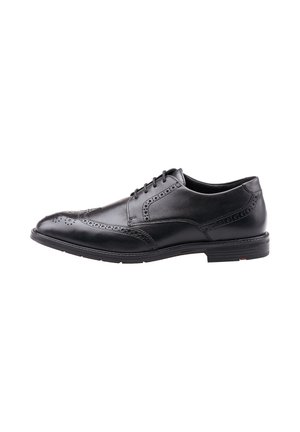 Zwarte leren heren wingtip Oxfordschoen met brogue-details en zwarte rubberen zool, zijaanzicht op witte achtergrond.