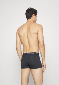 Boxeri din bumbac de culoare gri închis, cu un elastic alb cu marcă, design ajustat, textură netedă și fără modele sau accente vizibile.