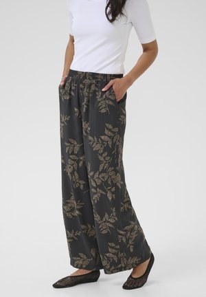 Pantalons noirs avec un motif de feuilles dorées, en tissu léger, avec une taille élastique et des poches latérales. Associés à des ballerines noires en toile.