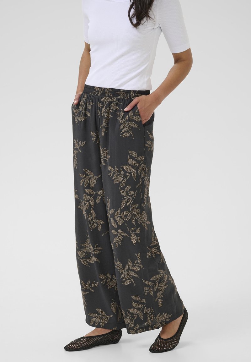Black pants with gold leaf pattern, lightweight fabric, elastic waistband, and side pockets. Paired with black woven flats.