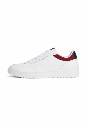Baskets basses blanches avec détail en mesh rouge, design à lacets et texte brandé "Tommy Hilfiger" sur le côté.
