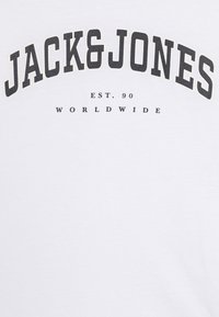 White t-shirt featuring "JACK&JONES" in bold black letters, with "EST. 90" and "WORLDWIDE" printed underneath in smaller font. Soft texture.