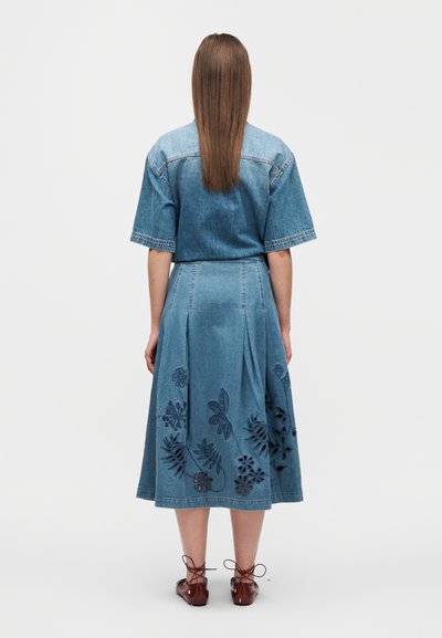 Robe en jean à manches courtes, avec une jupe évasée. Motifs floraux brodés en bleu foncé sur l'ourlet inférieur. Lavage bleu clair.