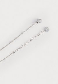 Collana in argento con chiusura a moschettone, ciondolo rotondo e una combinazione di segmenti di catena collegati e catena fine. Texture metallica liscia.