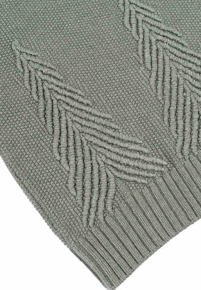 Tessuto a maglia verde chiaro con texture che presenta motivi di foglie in rilievo. L'orlo ribattuto in basso aggiunge un dettaglio strutturale.