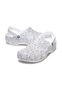 Witte klomp met een zilveren glitterpatroon, gemaakt van lichtgewicht materiaal. Bevat ventilatiegaten, een achterband en een ronde logo-accent.