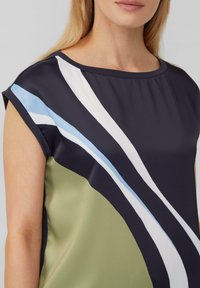 Elegantes navy-blaues Oberteil mit kurzen Ärmeln, verziert mit geschwungenen Streifen in Hellblau, Weiß und olivgrün. Glatte Stoffstruktur, runder Ausschnitt.