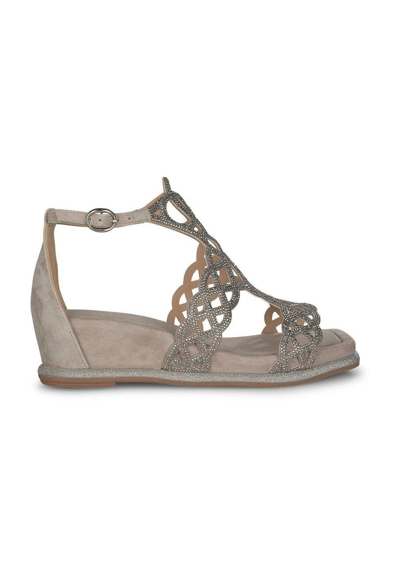 Sandalia de cuña beige con parte superior de ante, diseño decorativo de cortes y acentos metálicos. Correa ajustable en el tobillo y suela texturizada.