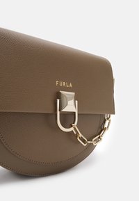 Hnědá kožená kabelka Furla s kulatým dnem, zlatým zapínáním a krátkým řetízkem na předním klopě.