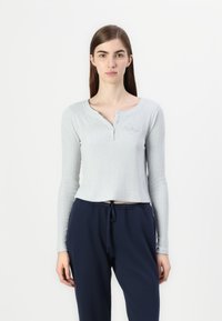 Lichtgrijze geribde lange mouw top met een henley halslijn en delicate knoopdetails, gecombineerd met marineblauwe broek met trekkoord.