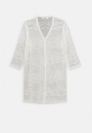 Cardigan en tricot crochet blanc avec devant ouvert, manches longues, et motifs circulaires et ondulés sur toute la surface.