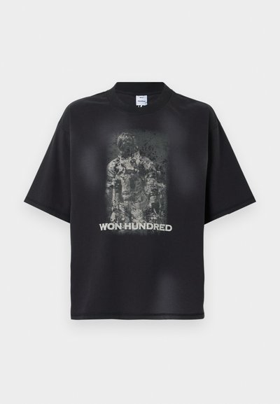 Czarny, oversize T-shirt z wyblakłą, szaroskalową grafiką astronoma i napisem „WON HUNDRED” poniżej obrazu z przodu.