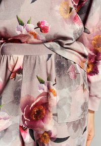 Bloemige lounge set met een roze basis, grote kleurrijke bloemen, een zachte stoftextuur en een elastische tailleband met logo-detail.