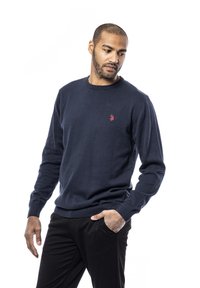 Marine crewneck sweatshirt lavet af blødt strikstof, med ribbet manchetter og kant, samt et lille rødt logo akcent på brystet.