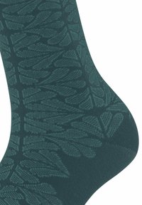 Turkusowa skarpeta z ciemnozielonym, misternym kwiatowym wzorem dzianym, pokrywającym okolice kostki i pięty, ukazująca szczegóły faktury tkaniny.