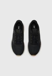 Baskets de sport noires avec un tissu texturé, des lacets et une semelle en caoutchouc lisse. Présente des accents de logo et un design à profil bas.