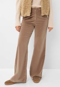 Wijd uitlopende broek van zacht, lichtbruin stof met een subtiele glans. Voorzien van een knoopsluiting en zijzakken, ontworpen voor comfort en gemak.