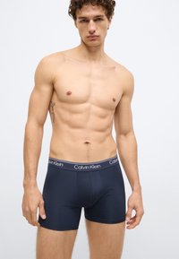 Cuecas boxer azul-marinho da Calvin Klein com cós com logótipo. Feitas de tecido macio, apresentam um design justo ao corpo e uma textura suave.