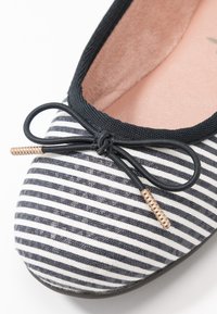 Gestreifte Leinenschuhballetschuhe in Marineblau und Weiß, mit schwarzer elastischer Borte und einem Schleifchen mit einem goldenen Hardwareakzent. Weiche Innenauskleidung.