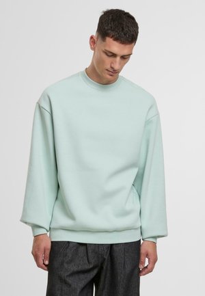 Svetlo mätová mikina s okrúhlym výstrihom, voľný strih a rebrované manžety a spodný lem. Mäkka, hladká textúra; minimalistický dizajn.