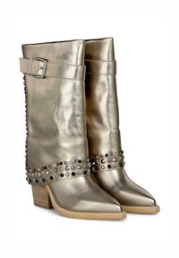 Bottes mi-mollet dorées métalliques avec des pointes en amande, des clous décoratifs le long de la base et un détail de boucle sur le côté. Talon en bois.