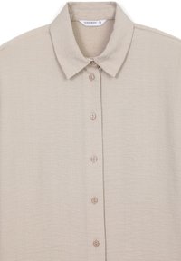 Camicia beige con bottoni, colletto classico, tessuto texturizzato e quattro bottoni marrone chiaro lungo il davanti. Taglia piccola.