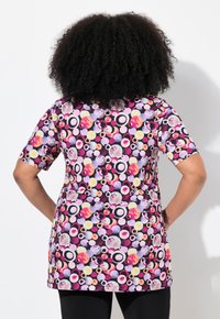 Túnica de manga corta con un vibrante patrón circular multicolor sobre un fondo negro. Fabricada con una tela suave y ligera.