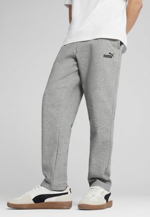 Grijze sweatpants in een relaxte pasvorm met zijzakken, voorzien van een zwart Puma-logo. Draag ze met witte en zwarte sneakers.