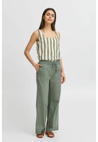Kreemjas ja oliivrohelises toonis triibuline tank top, millele on sobitatud laiad oliivrohelised püksid, millel on elastne vöökoht ja küljetaskud.