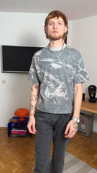 Tricou gri cu model și mâneci scurte, asortat cu blugi gri închis. Tricoul are un design inspirat din natură și o croială lejeră.