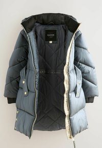 Chaqueta acolchada en color marino con un patrón de rombos, que presenta una cremallera y herrajes en dorado claro, y un suave forro interior negro.