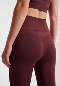 Leggings color bordeaux a vita alta realizzati con materiale strutturato, con design senza cuciture e sottili dettagli a coste vicino alla vita e ai lati.