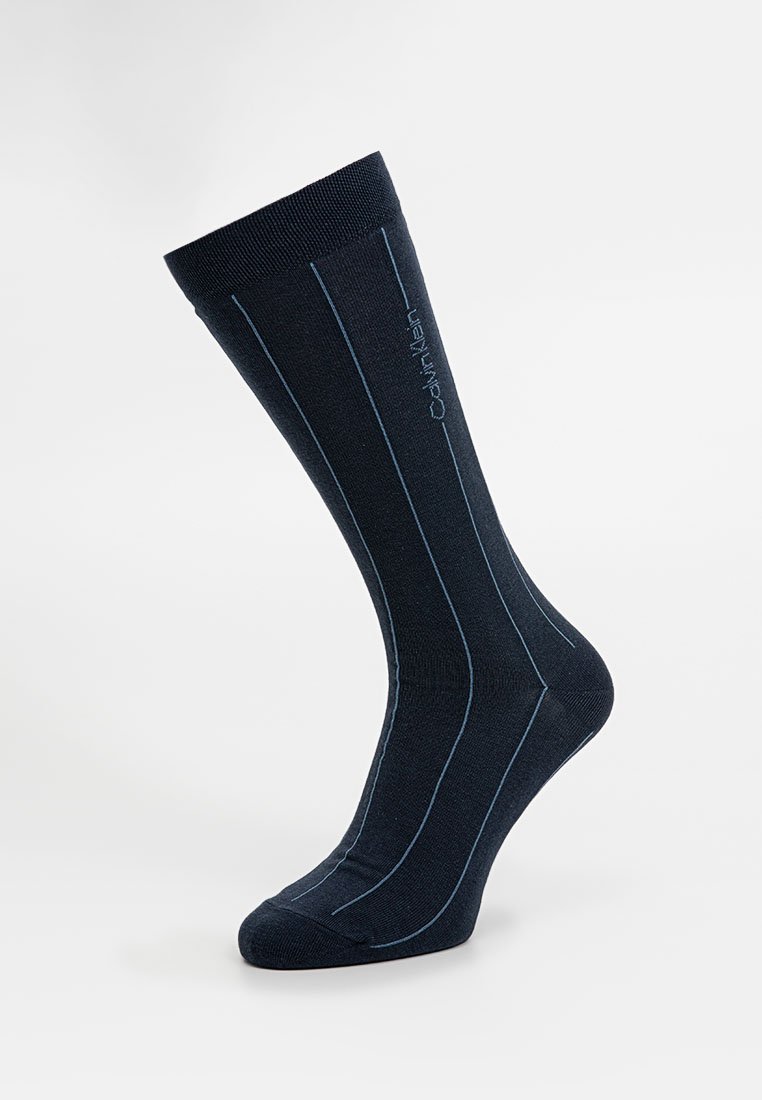 Marineblaue knielange Socke aus dehnbarem Material mit hellblauen vertikalen Streifen und Logo-Detail am oberen Ende. Glatte Textur.