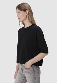 Czarny bawełniany t-shirt o luźnym kroju, krótki rękaw i okrągły dekolt, w połączeniu z jasnoszarymi dżinsami w slim fit.