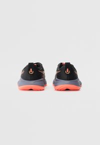 Black athletic shoes with pink-orange accents, featuring a textured fabric upper, cushioned sole, and a pull tab at the heel for easy wear.