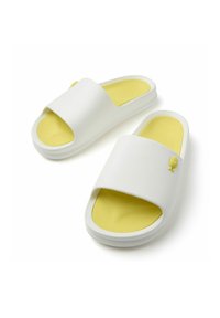 Sandalias blancas de pala ancha y sin hebilla, con plantilla amarilla y un pequeño detalle amarillo. Material suave y diseño redondeado.
