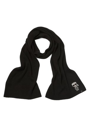 Zwarte gebreide sjaal met een lusvormig midden en een klein cartoonfiguurtje met zonnebril op één uiteinde, weergegeven tegen een witte achtergrond.