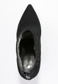 Stivale alla caviglia nero con punta affusolata, in materiale scamosciato, dettagli in pizzo sui lati, chiusura con cerniera sul retro e interno decorato.
