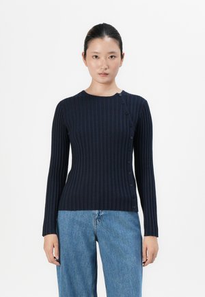 Navy ribbed knit sweater featuring long sleeves, round neckline, and a side button closure. Paired with light blue loose denim jeans.