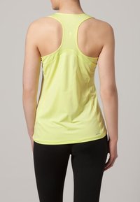 Ljust gul träningslinne med racerback-design, med nätpaneler för andningsförmåga och en mjuk textur. Svarta leggings nedanför.