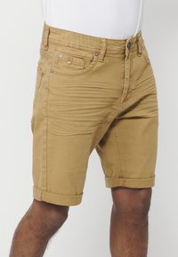 Shorts khaki en tissu mélangé coton, avec une coupe slim, ourlet retroussé, poches avant, passants de ceinture et accents en métal.