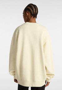 Sudadera de corte oversized en color crema, con hombros caídos, puños y dobladillo acanalados. Tejido de felpa suave y ajuste relajado para mayor comodidad.