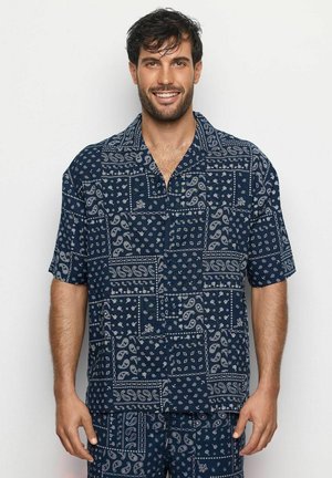 Marineblauw overhemd met korte mouwen, voorzien van een paisley- en geometrisch patroon in wit. Kraagontwerp en een relaxte pasvorm met een knoopsluiting aan de voorkant.