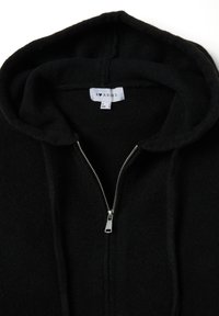 Felpa nera con cerniera centrale realizzata in tessuto morbido con texture in pile. Presenta una cerniera argentata e un cappuccio con coulisse e etichetta interna.