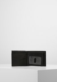 Sort læderpung med flere kortpladsser, et ID-vindue og en tekstureret overflade. Kompakt rektangulær form, åbnet på en hvid overflade.