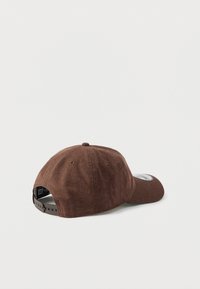 Καφέ υφασμάτινο καπέλο με στρογγυλεμένο σχήμα, διαθέτει κεντημένο λογότυπο σε επιθεματάκι και ρυθμιζόμενο πλαστικό λουράκι στο πίσω μέρος. Μαλακή υφή.